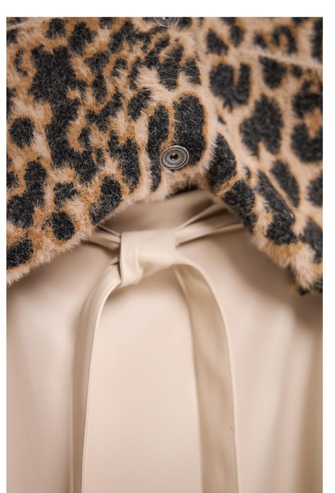 Detail van een luipaardprint kraag boven een crèmekleurige blouse